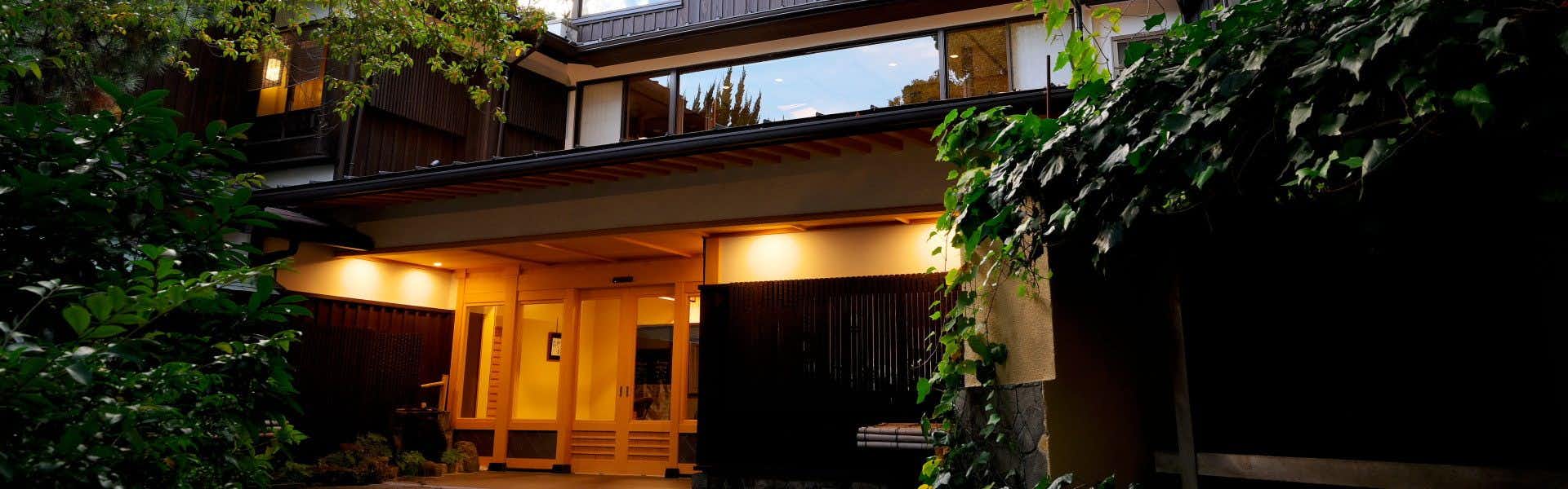 Atami Onsen Sanpeiso with this scene, where sanpeiso's traditional facade glows beneath dense garden foliage after dark.