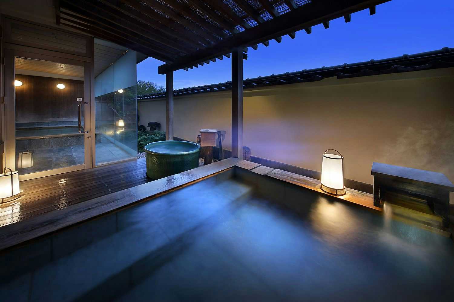 Atami Onsen Sakuraya Ryokan Circular pool with wooden deck surround, latticed overhead structure, glass doors, and interior lighting.