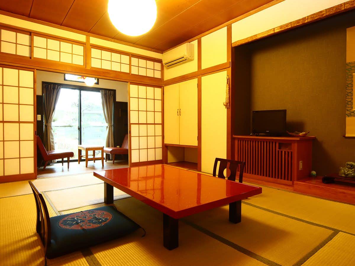 Togura Kamiyamada Onsen Aritaya Ryokan with a warm tatami guest room with a red lacquer table and shoji windows.