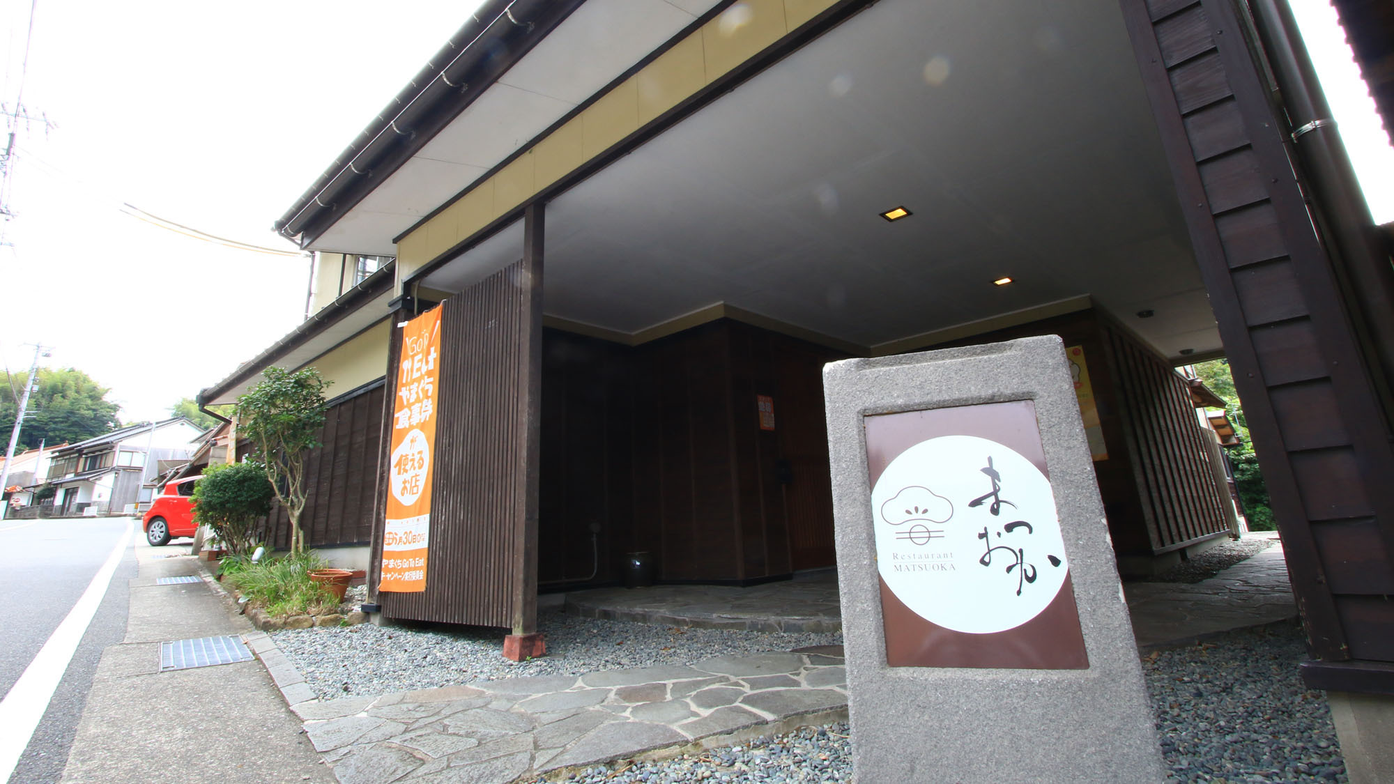 The dark timber entrance beside a white property sign.