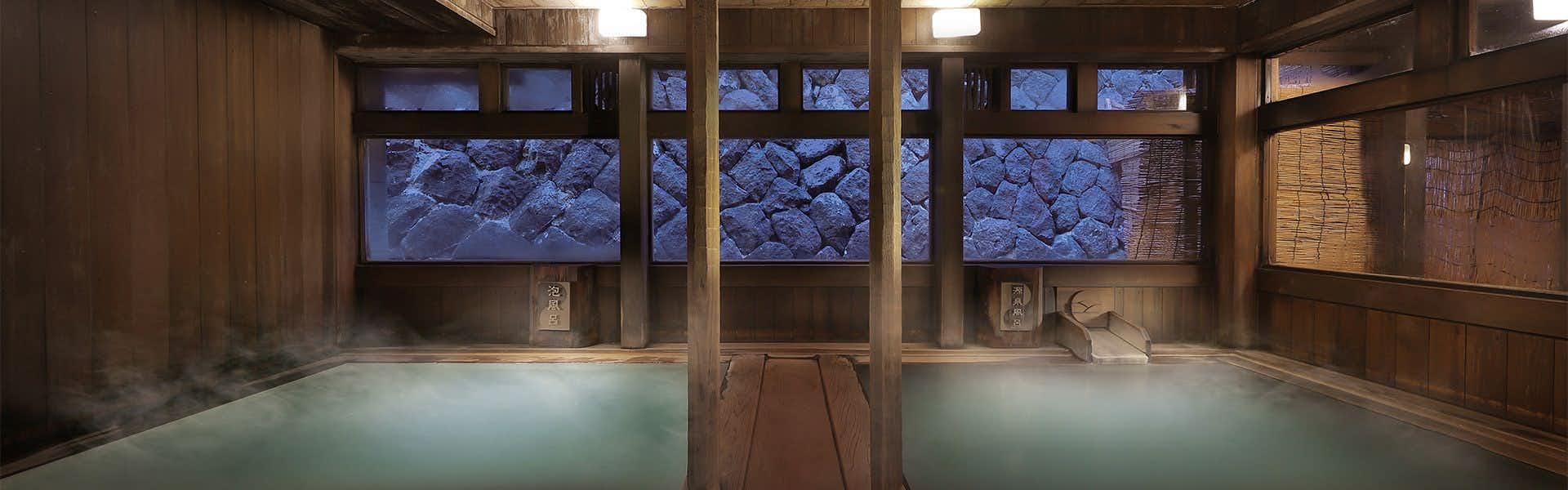 Omiya Ryokan with a timber-lined indoor bath beside dark stone walls.