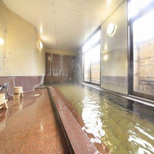Ryokan Yunoya with a long indoor bath beside broad windows and tiled walls.