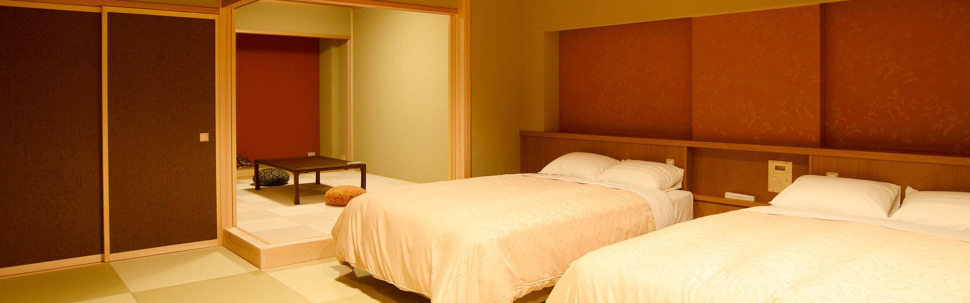 Manten no Yado: All Rooms Equipped with Open-Air Natural Hot Springs with twin beds beside a warm timber accent wall.