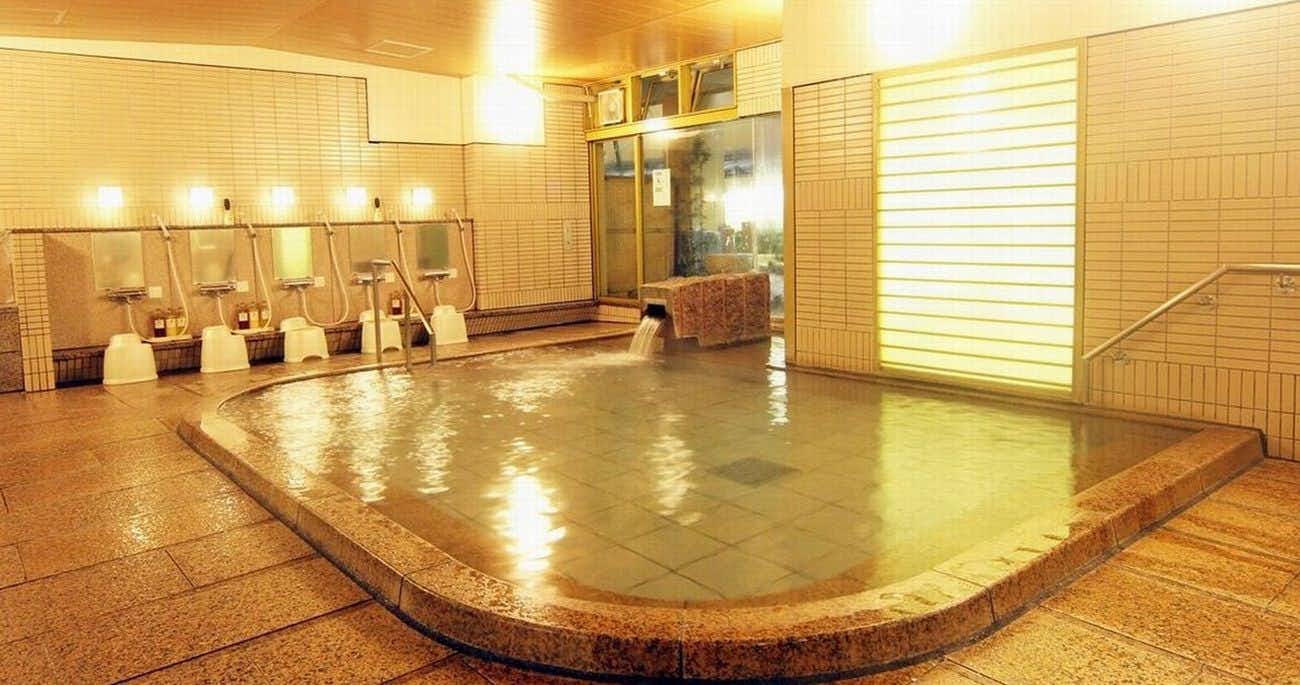 Miyajima Hotel Makoto with a broad indoor mineral bath lined with pale tiles.
