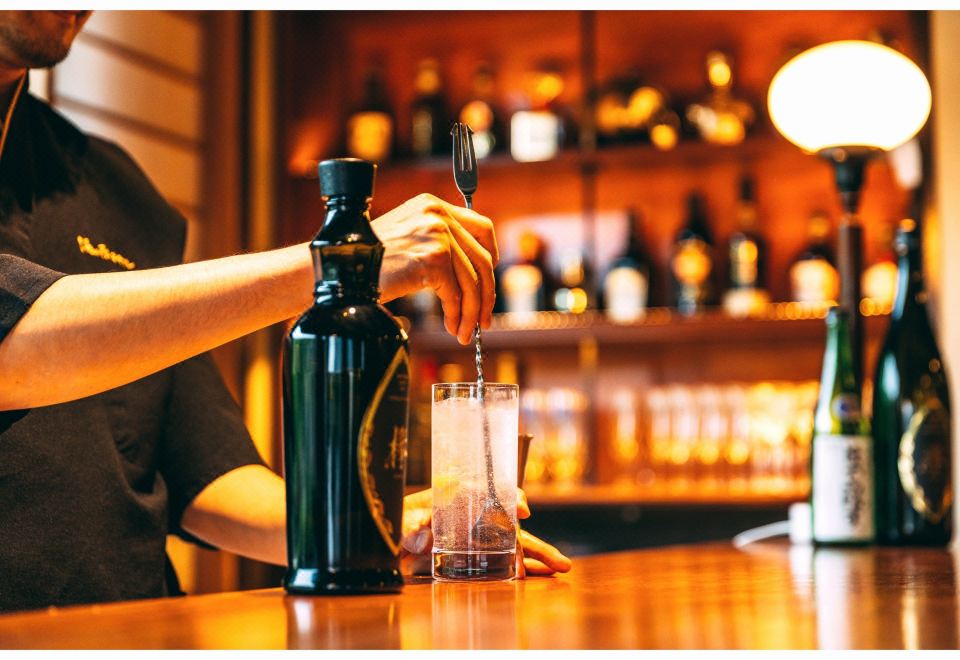A bar counter with bottles and a seated person.