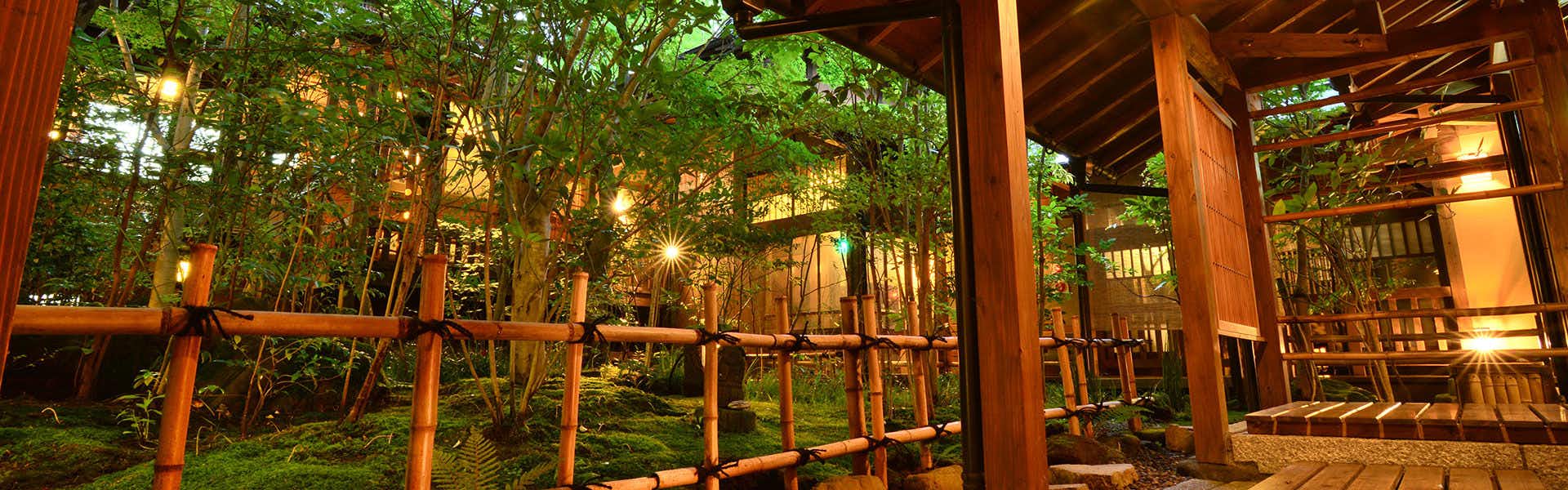 Kurokawa Onsen Oyado Noshiyu covered walkway with bamboo rails overlooking an illuminated garden
