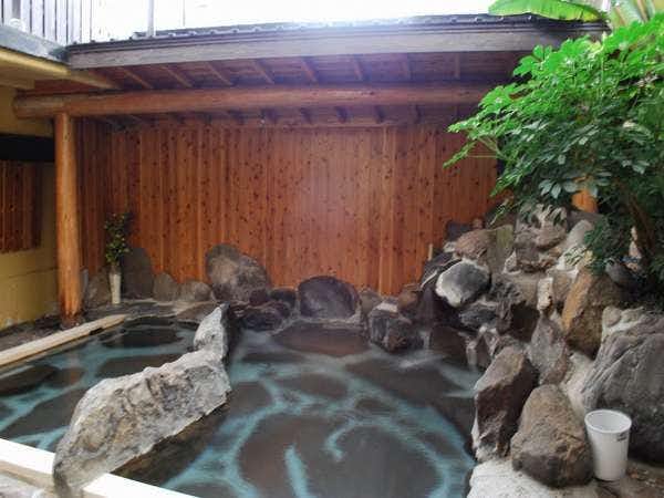 Yuyado Tsurumisou with an outdoor stone bath surrounded by warm timber walls.