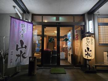 The glass entrance door between a fabric banner and an illuminated sign.