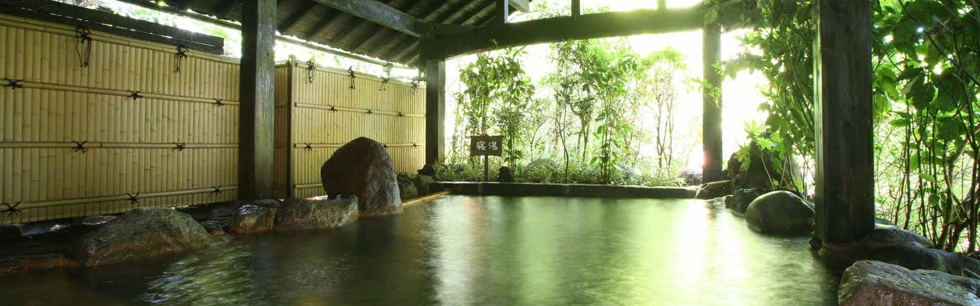 Ryokan Wakaba an open-air rock bath enclosed by a bamboo screen.
