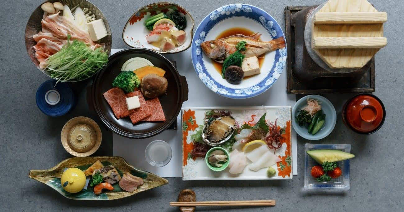 Kakurega Yukari with a Japanese dinner arranged around sashimi, beef, and ceramic side dishes.