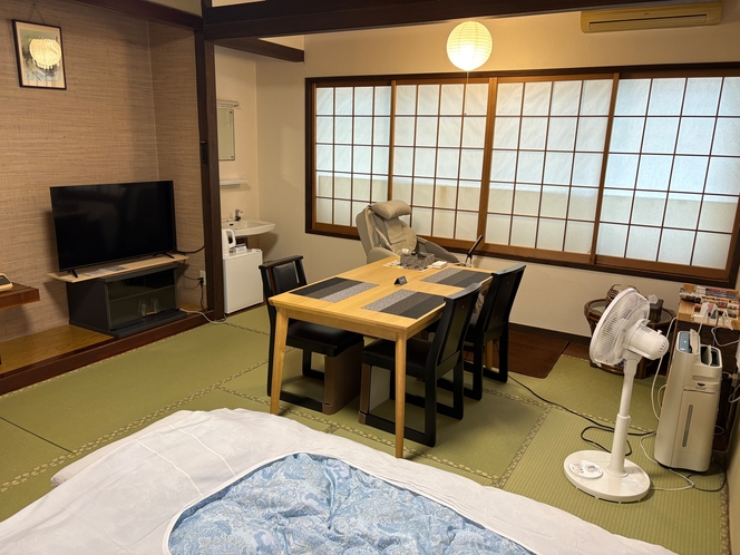 A tatami room with bedding, a table, and a massage chair.