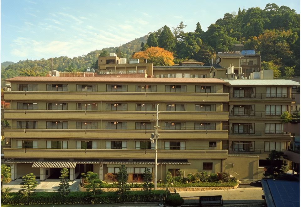 The multi-storey ryokan facade beneath wooded hills.