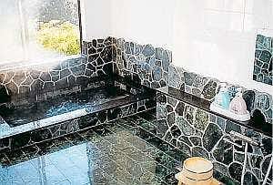 Ikoi Sanso with a compact stone-lined bath beside patterned tile walls.