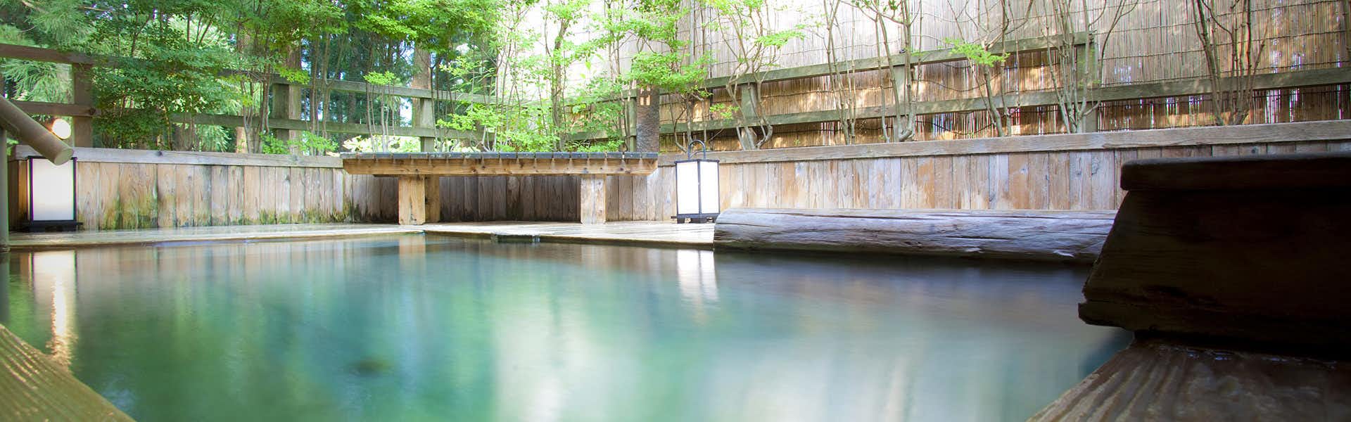 Ichirino Kogen Hotel Roan with a large open-air mineral bath surrounded by leafy trees.