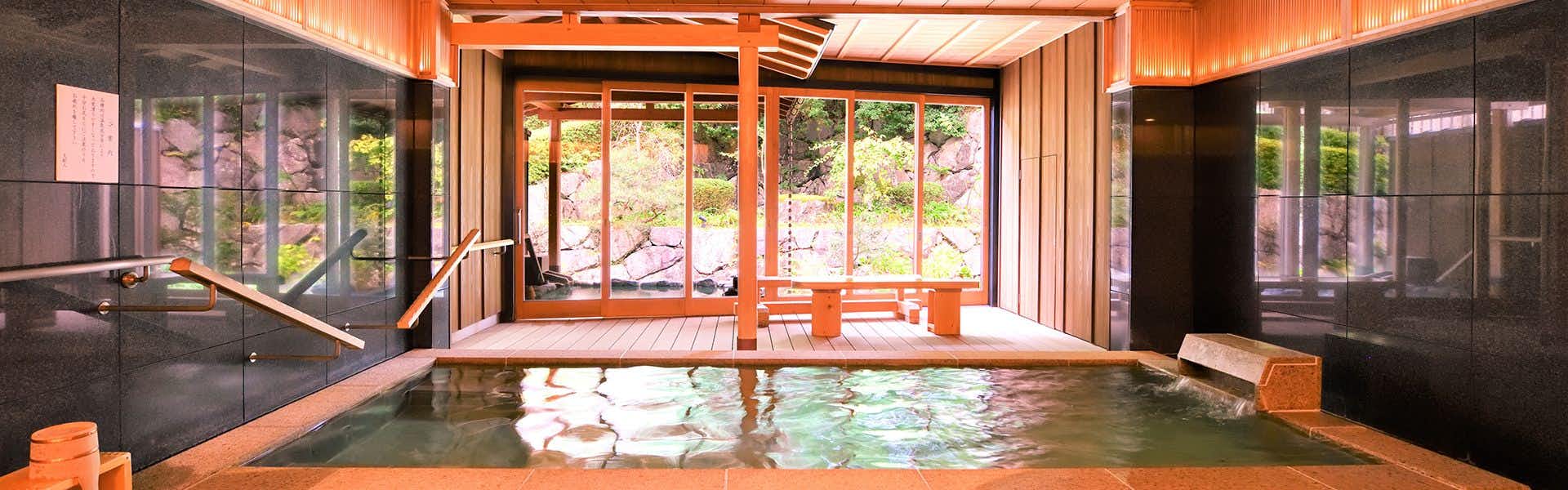 KYO YUNOHANA RESORT Suisen with an indoor pool, orange beams, dark walls, and open garden doors