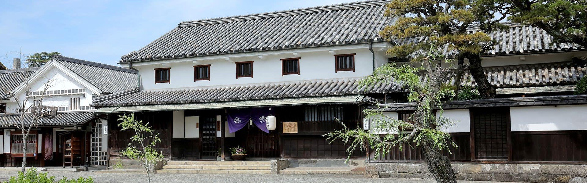 Ryokan Tsurugata with a white traditional facade with dark tiled roofs and garden pines.