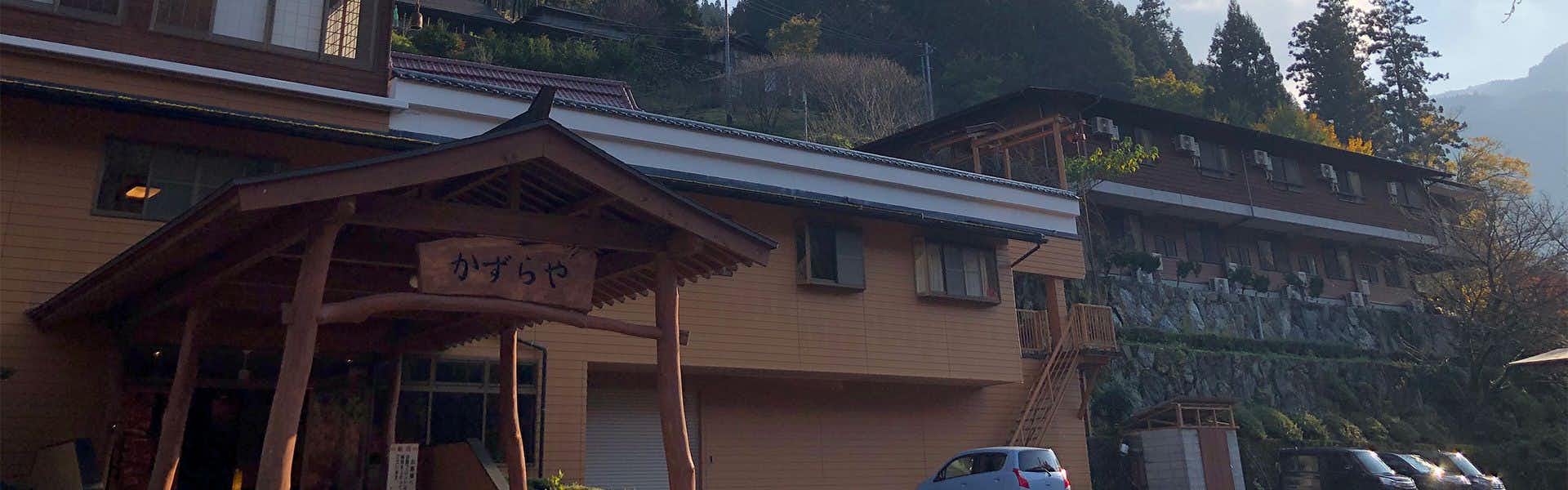 Iya no Yado Kazuraya with the traditional entrance beneath forested mountain slopes.