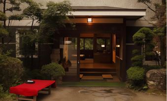 Garden entrance porch with a red bench, stone paving, and trimmed shrubs.