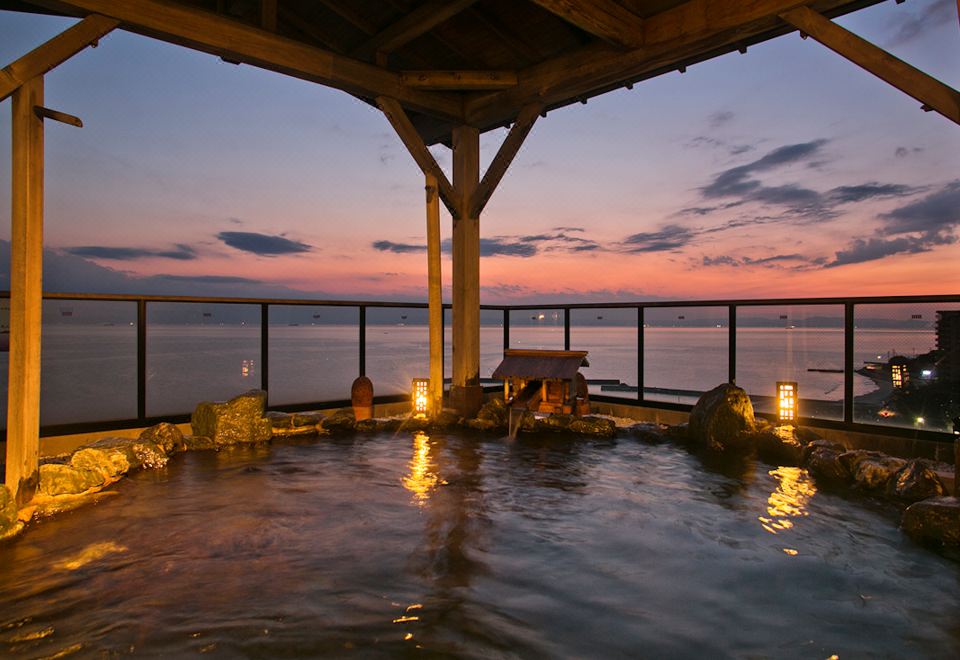 An open-air bath overlooking the sea at dusk.