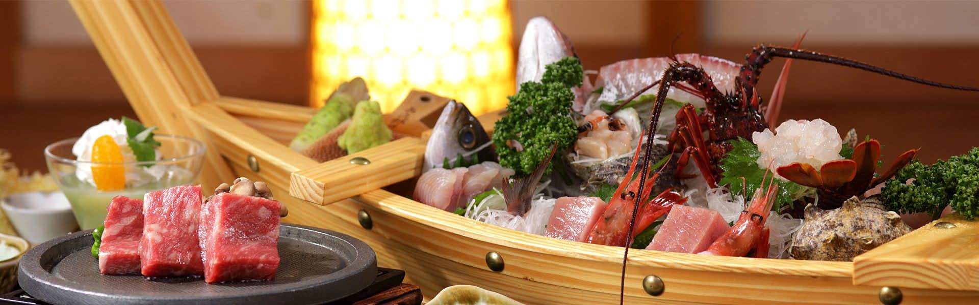 Nishi-Izu Toi Yagisawaso with this scene, where a boat of sashimi and a small tabletop grill present part of the evening meal.