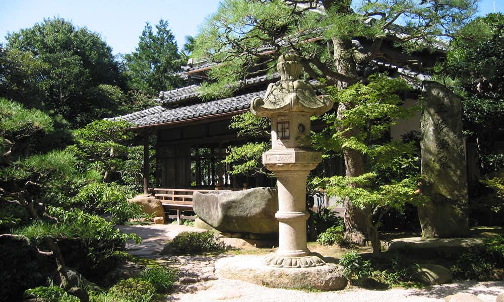 Hoshokan with a manicured garden with stone lantern and evergreen trees.
