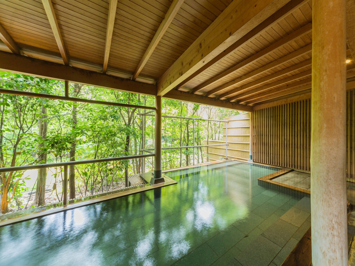 A covered bath overlooking green trees.