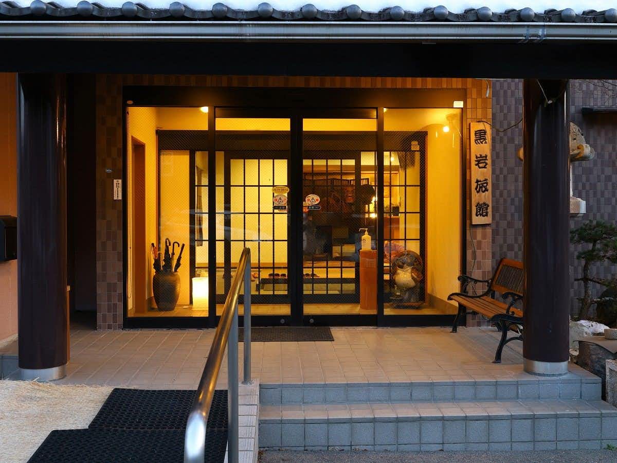 Kakeyu Onsen Kuroiwa Ryokan with this scene, where a covered entrance frames the warmly lit doors of Kuroiwa Ryokan.