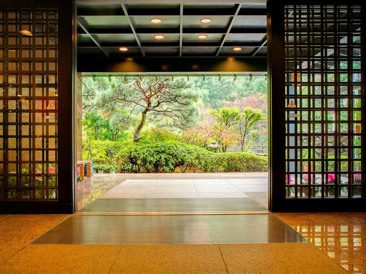 Forest Resort Yunonosato Sugina with a timber-framed entrance opening toward a garden courtyard.