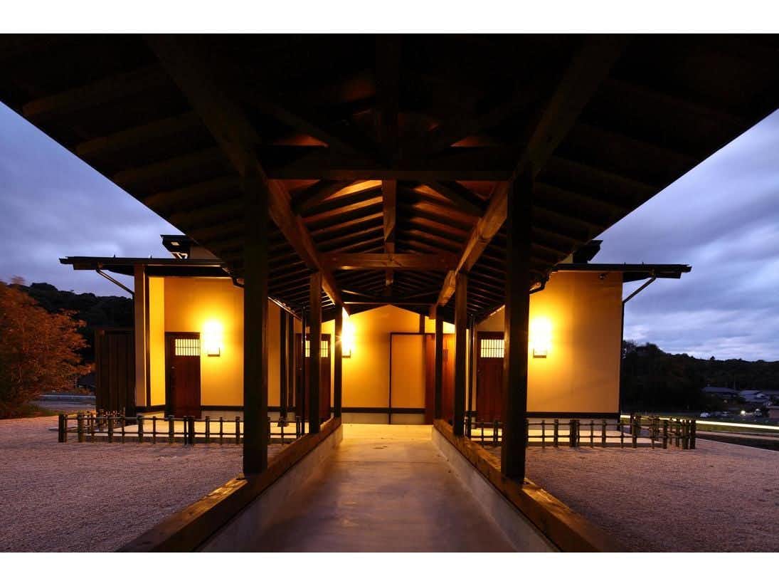Yumoto Yunokawa with a covered timber walkway leading toward illuminated guest buildings.