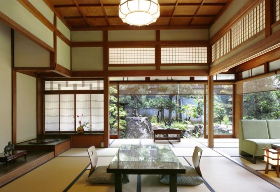 A traditional guest room with a low table and broad windows facing a garden.