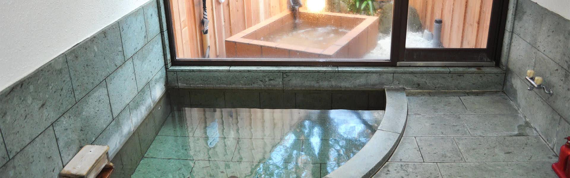 Imaihama Onsen Ryokan Kokoro Nodoka with clear mineral water flowing through a dark stone bath.