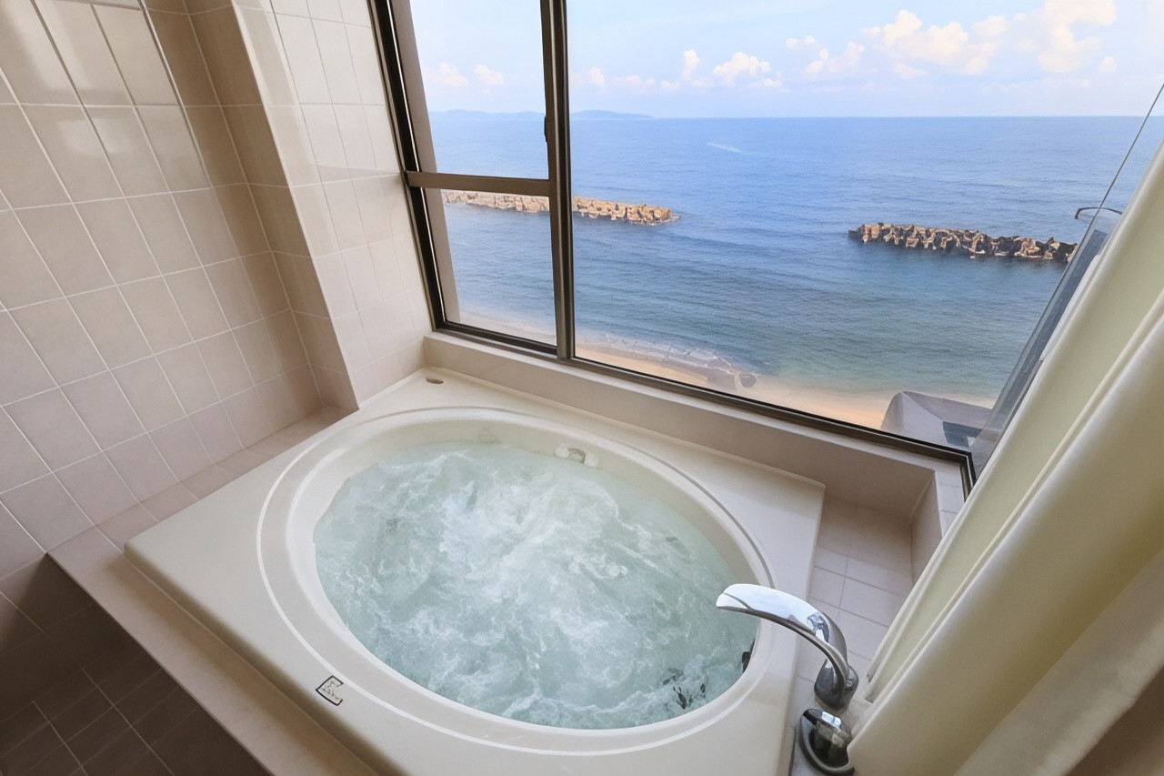 A round bath sits beside a window overlooking the sea.