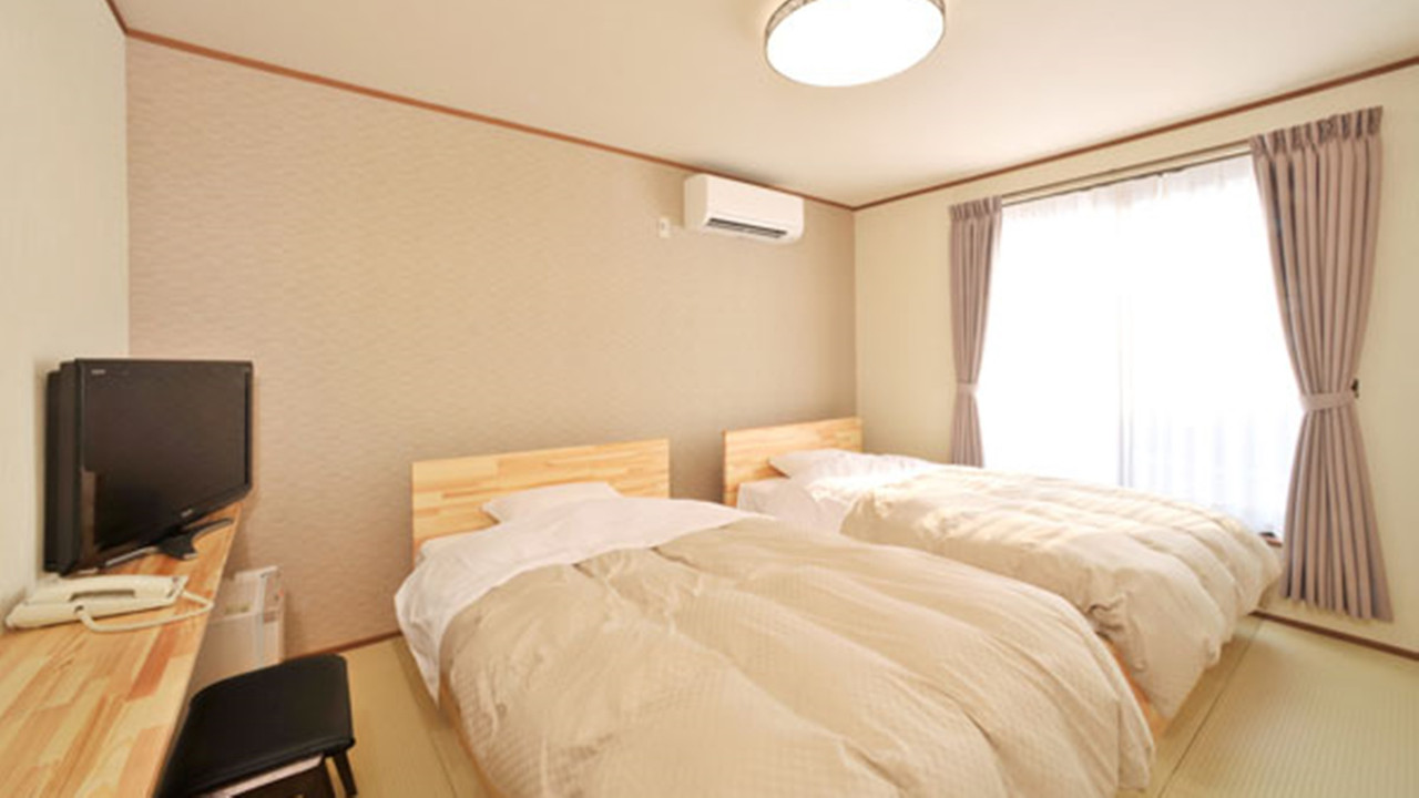 A room with twin beds and a large window.