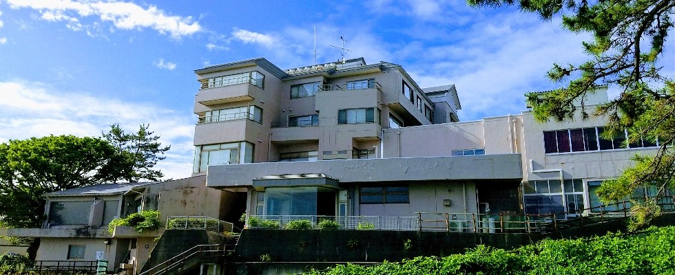 Its seaside exterior framed by mature green trees.