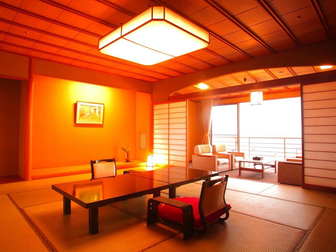 Eihokaku with a warmly lit tatami room with low table and ocean windows.