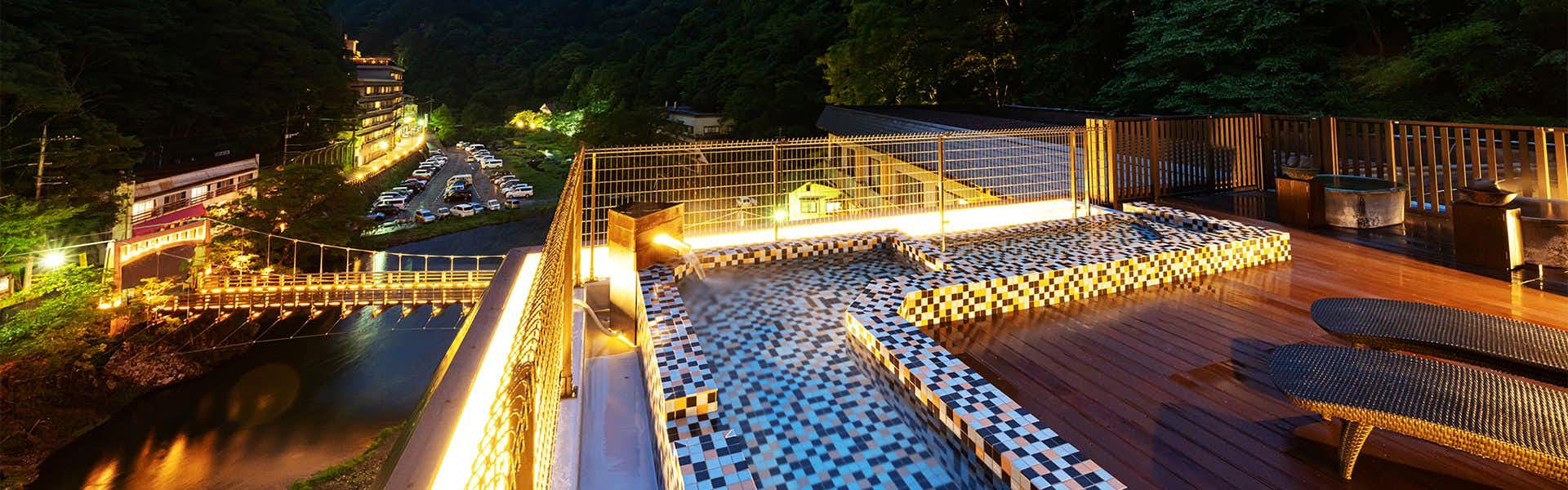 Hakkei with a glowing suspension bridge reflected across the river at night.