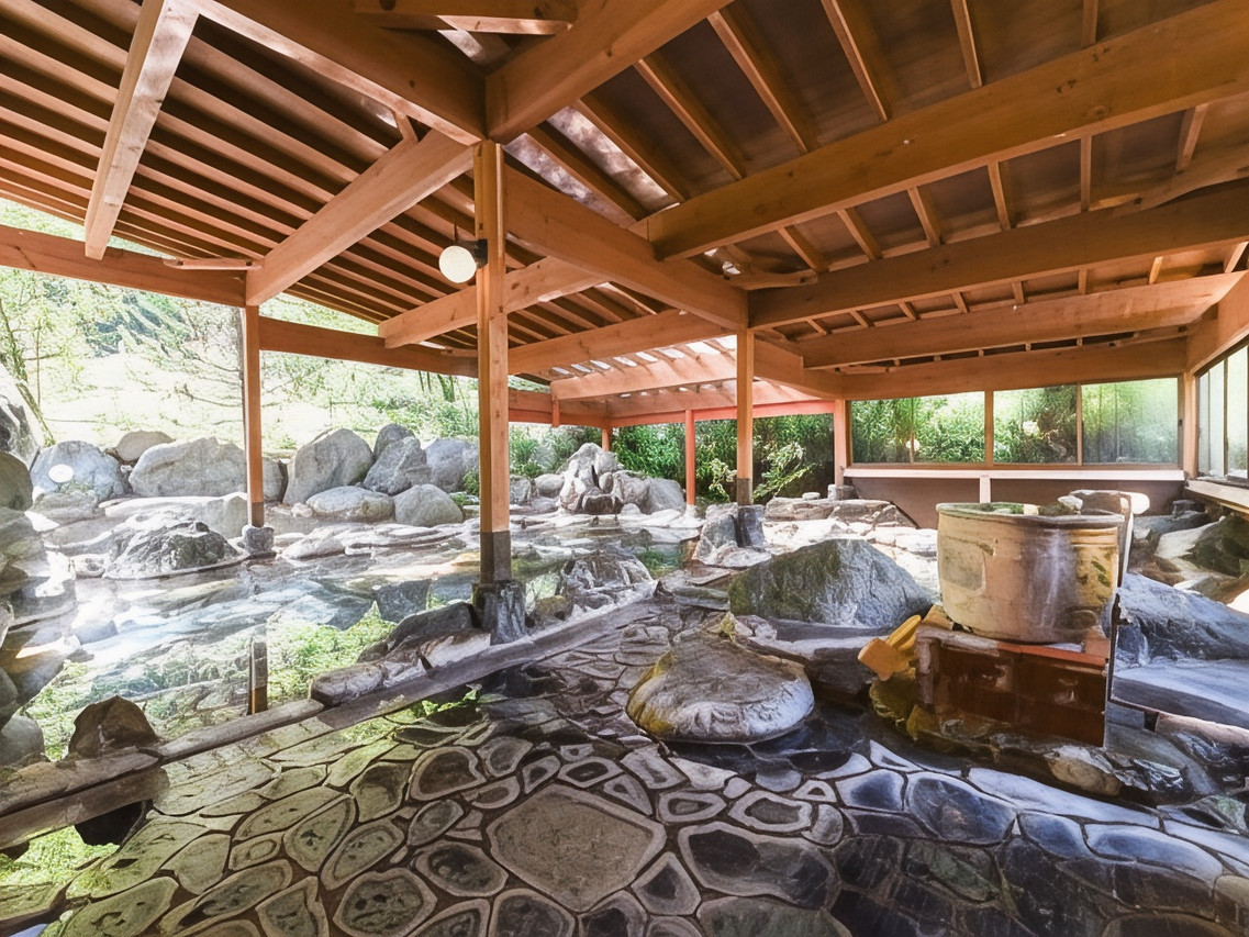 A covered rock bath sits beneath a timber roof.
