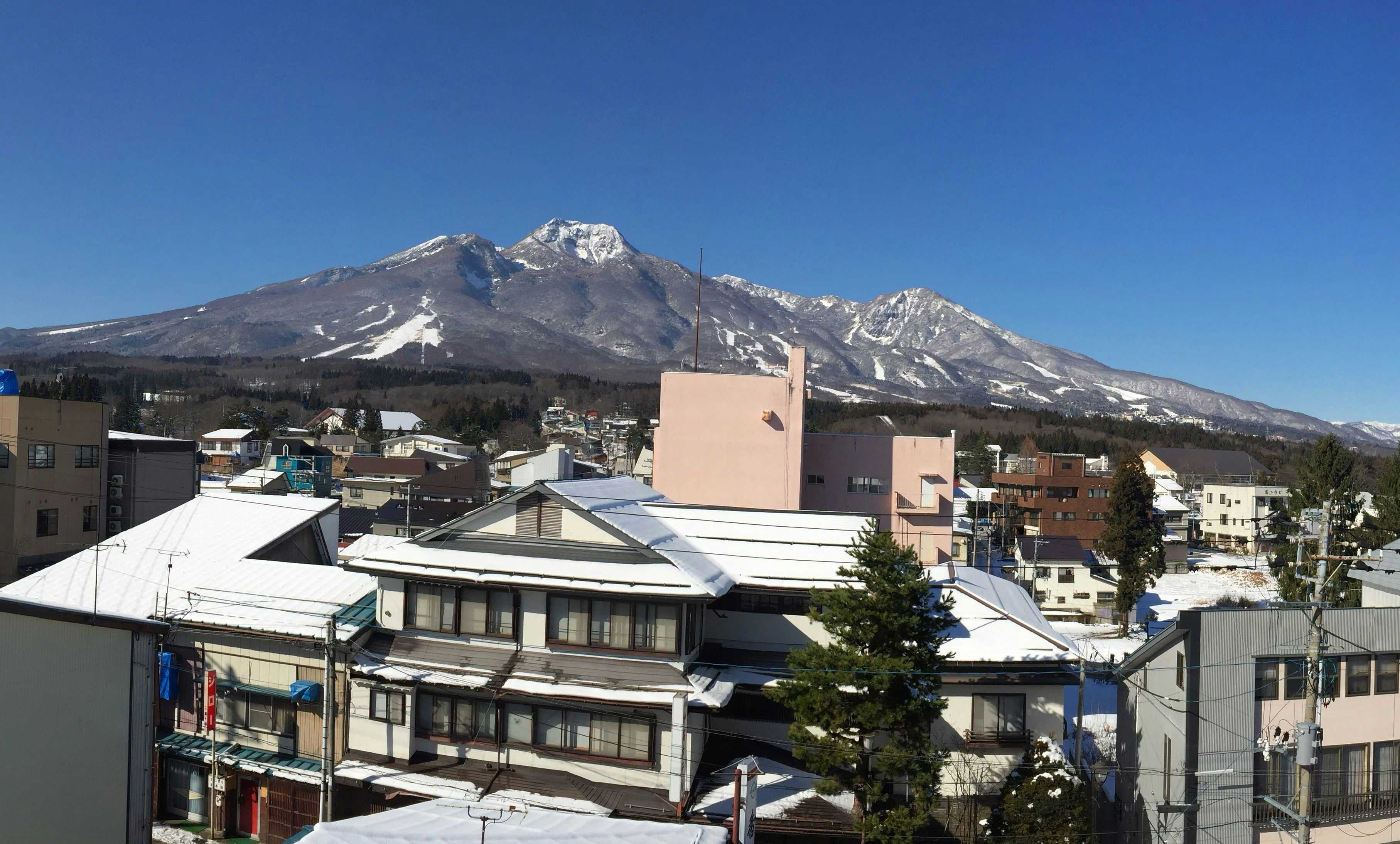 Myoko Yamasato no Yuyado Kofukan with a clear panorama of snow-streaked Myoko mountain peaks.