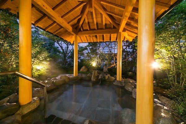 Mutsumi Inn with a covered open-air bath glowing beneath timber rafters.