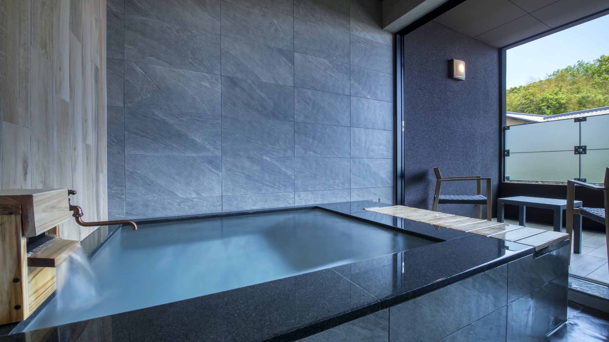 A rectangular stone bath beside an open terrace.