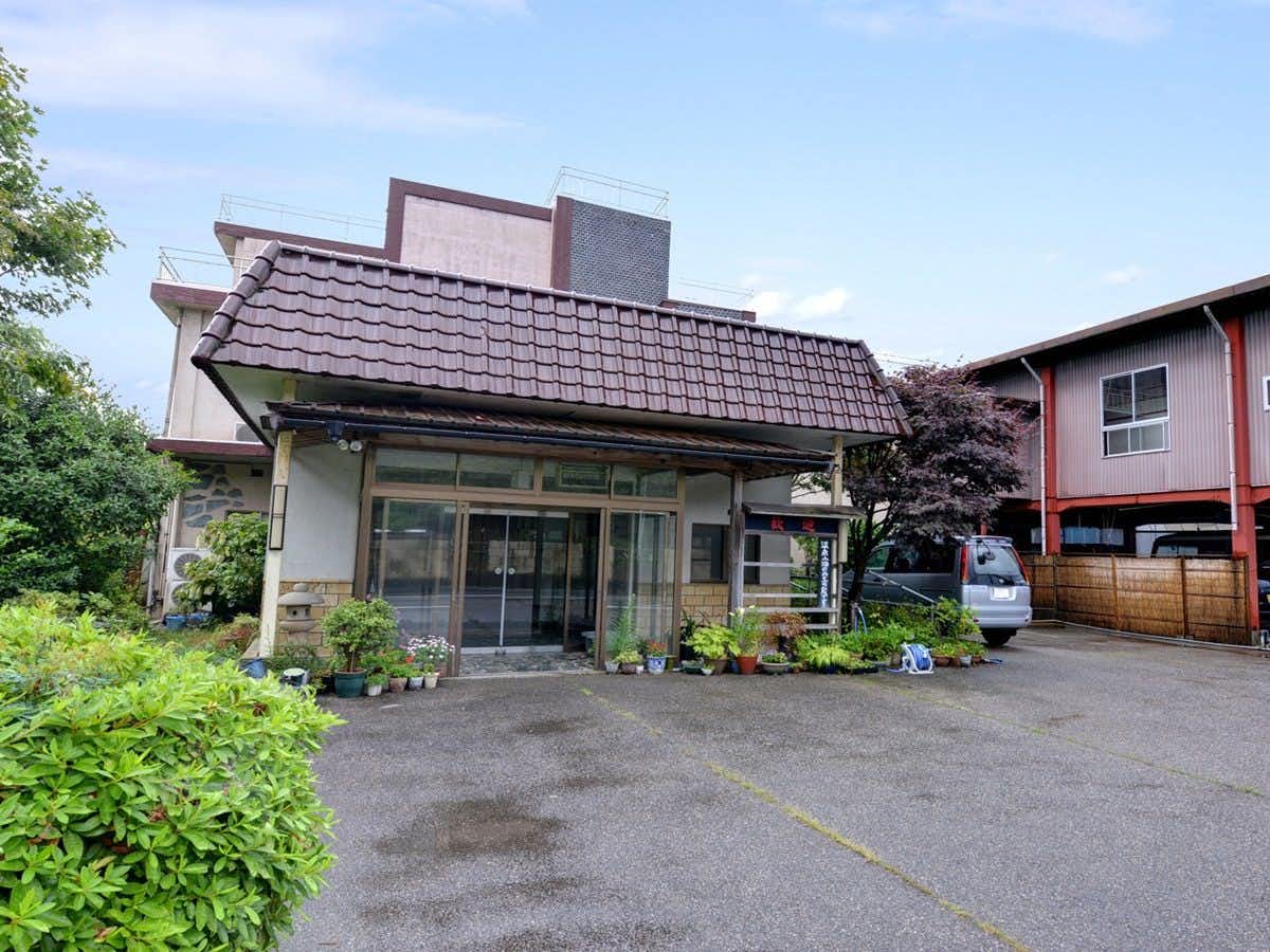 Takase Onsen Hanamichiru Yado New Manriki with the modest roadside inn beneath a pale sky.