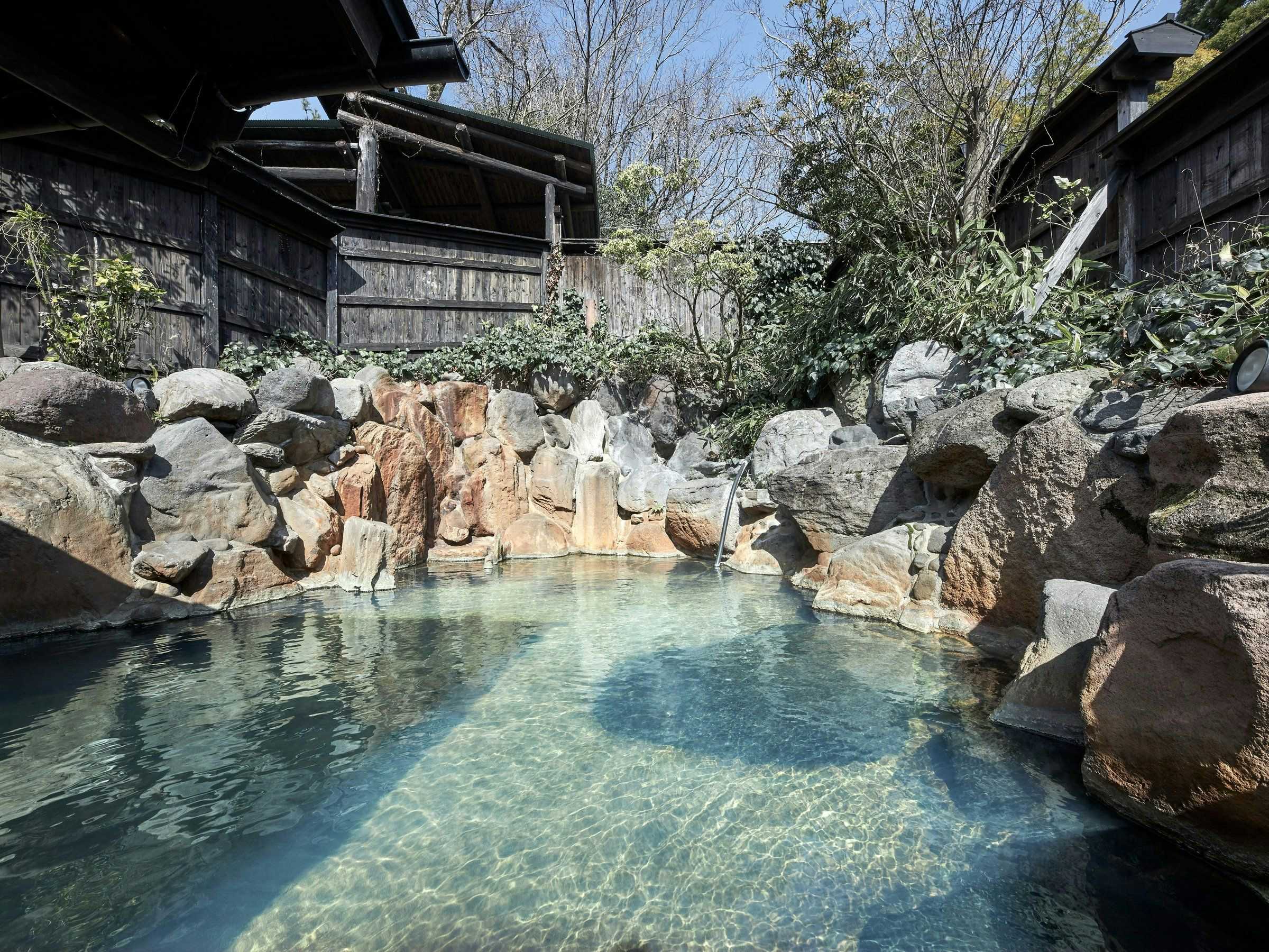 Ryokan Yamanoyu with a broad outdoor rock bath surrounded by pale stone.