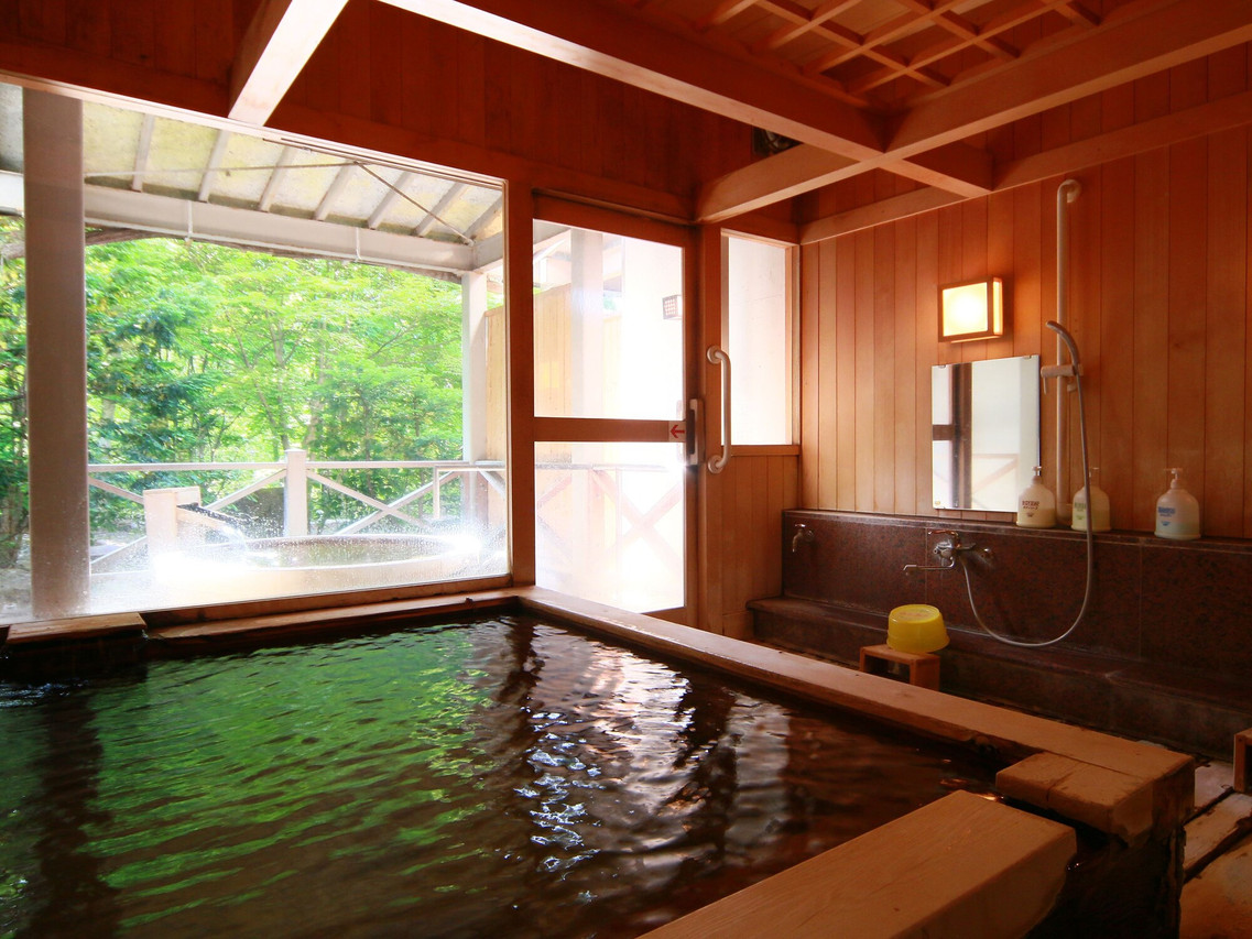A wooden bath opens toward a leafy outdoor view.