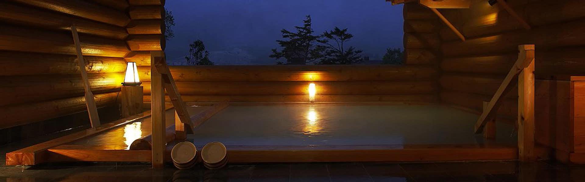 Hakugin no Yu Manzatei with an open-air mineral bath glowing beneath a dark sky.