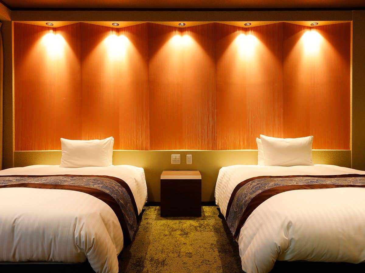 Kurama Onsen Masagokan with this scene, where twin beds sit beneath warm wall lighting in a contemporary guest room.