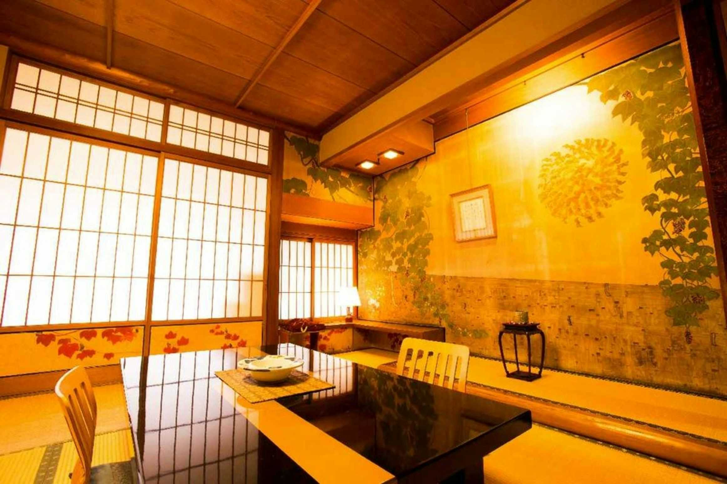 Kinosaki Onsen Tsutaya Ryokan with an intimate dining room decorated with golden floral artwork.