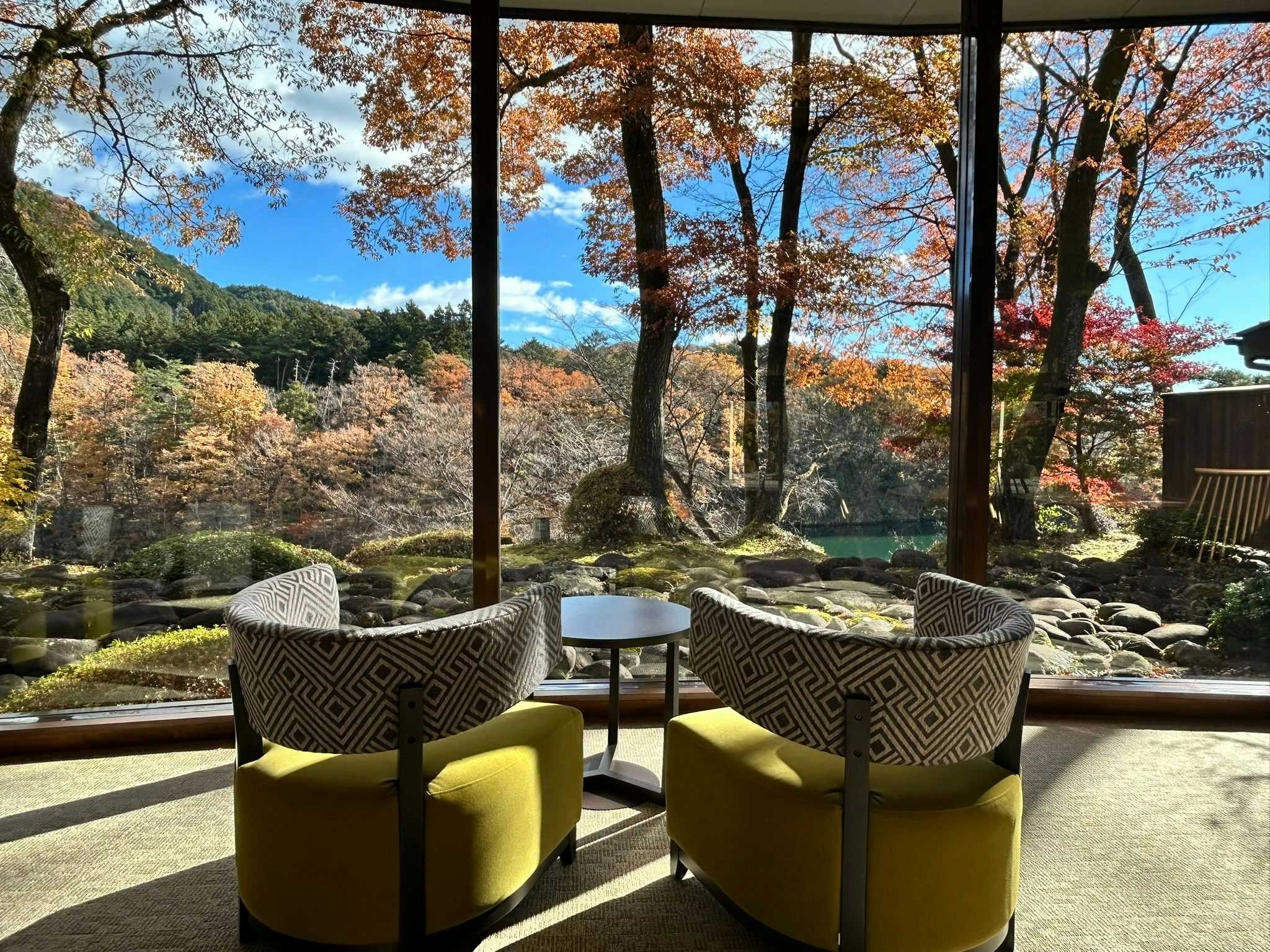 Kinuno Yado Shiki Ootoro with green lounge chairs overlooking autumn trees and a quiet garden.