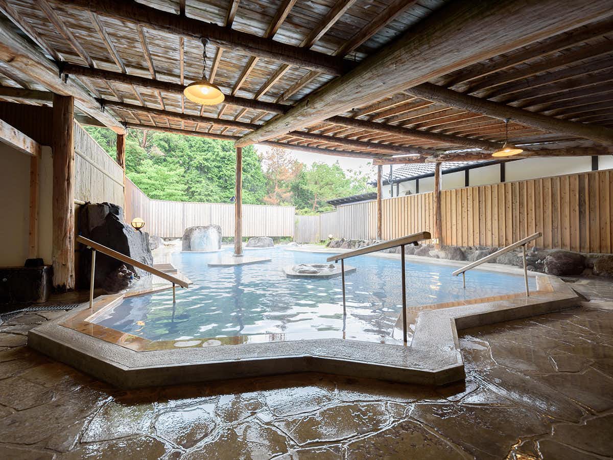 Yufuin Onsen Tsukanoma with a broad open-air bath beneath a timber canopy.