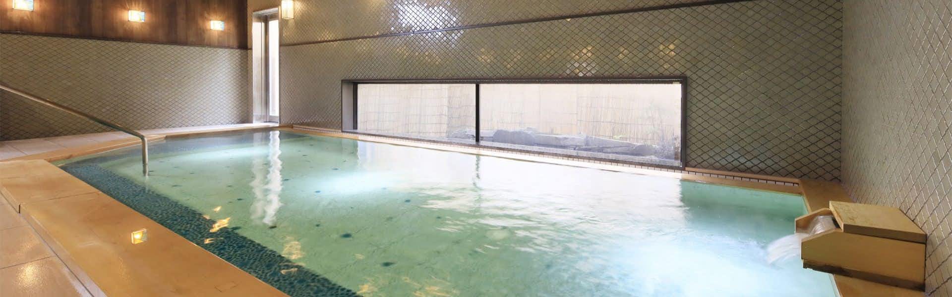 A spacious indoor bath lined with dark mosaic tile.