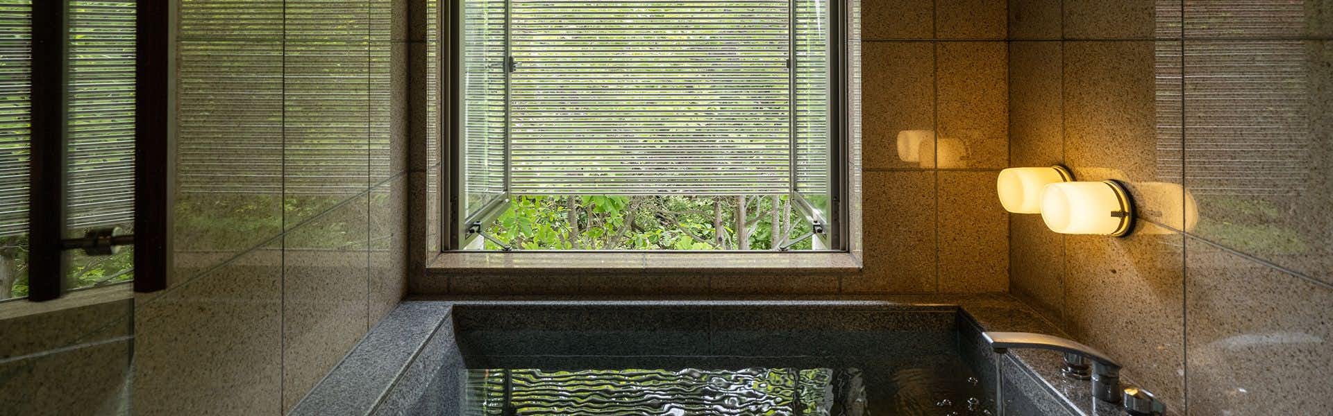 Otaru Ryotei Kuramure with a private stone bath beside frosted garden windows.